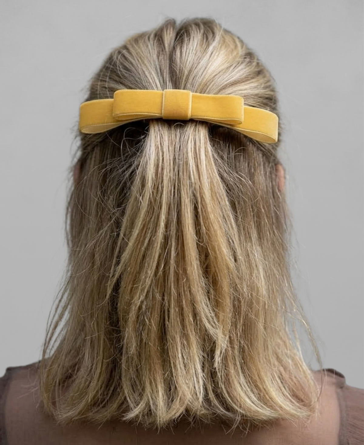 Nœud minimaliste élégant, au jaune éclatant, porté en demi-queue par une jeune femme blonde.