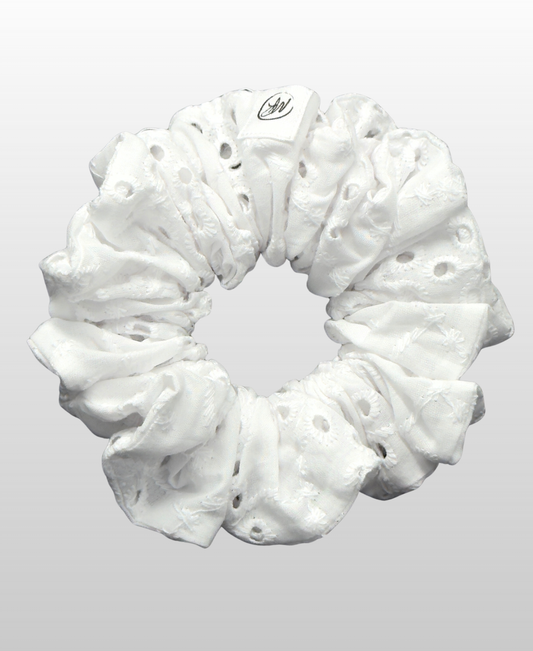 Chouchou confectionné en broderie anglaise 100 % coton dans une teinte blanche neutre, avec des perforations et des motifs floraux brodés.