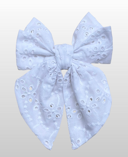 Montée sur une barrette dorée à l’or fin, le nœud Melis est fabriqué en broderie anglaise blanche.