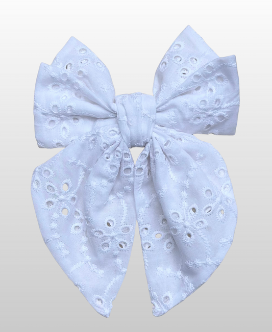 Montée sur une barrette dorée à l’or fin, le nœud Melis est fabriqué en broderie anglaise blanche.
