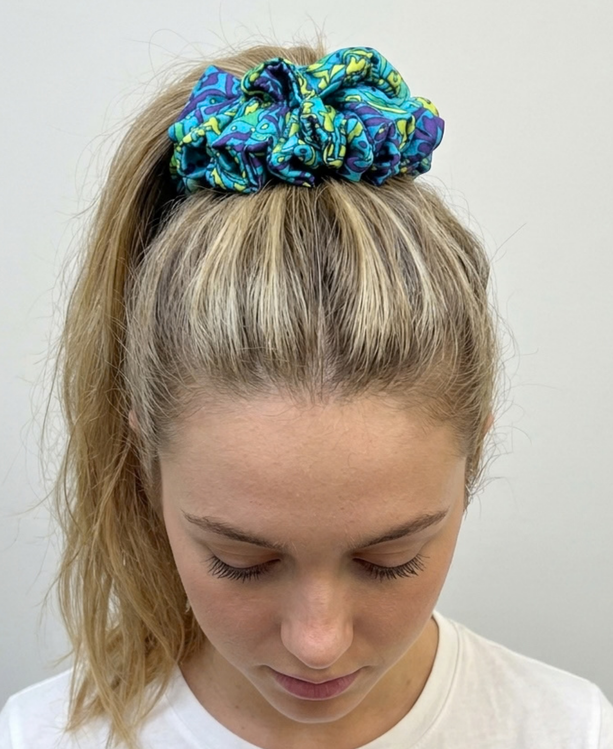 Chouchou en satin de soie bleu turquoise, avec des touches de violet et de vert anis porté en queue de cheval haute.