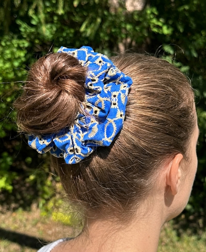Chouchou au bleu captivant, à la broderie anglaise dorée et beige sable porté en chignon haut.