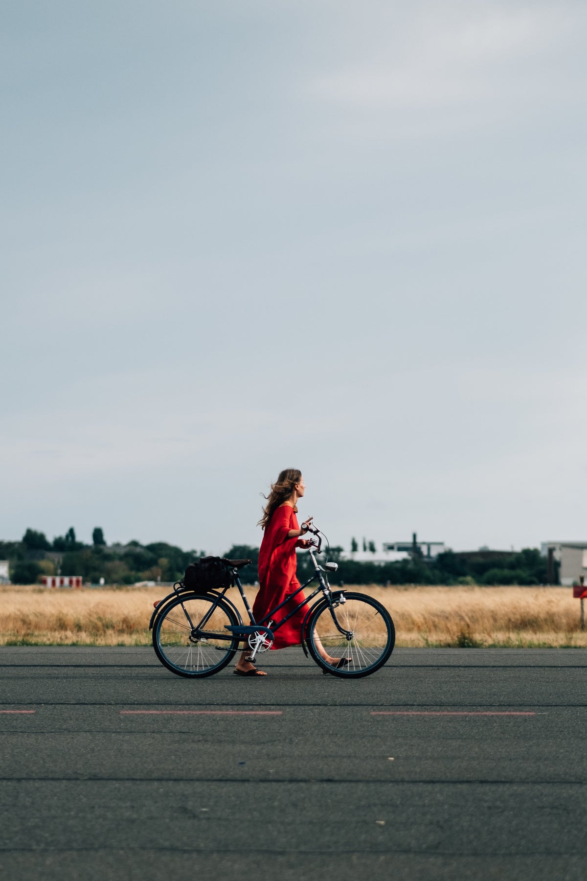 Une femme marche, son vélo en mains, sur la route de son avenir au sein de la maison Marylou Rose.